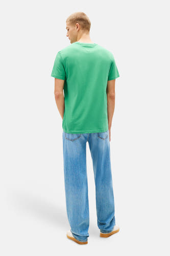 T-shirt vert à manches courtes TOMMY JEANS, avec un design uni et porté avec un jean ample et des baskets.