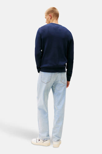 T-shirt bleu avec col rond de TOMMY JEANS, porté avec des jeans légers et des baskets blanches, vu de derrière.