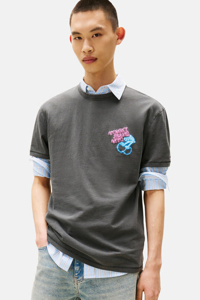 T-shirt gris à manches courtes de TOMMY JEANS, avec logo de cerises néon, associé à un chemisier rayé.