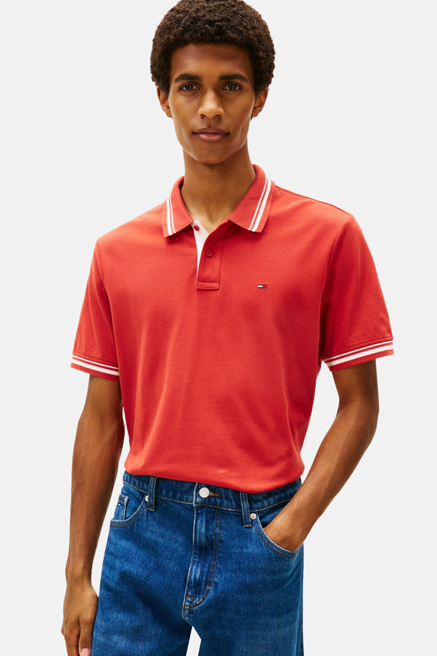 Man met rood poloshirt en blauwe jeans.