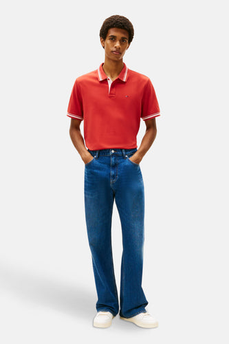 Man in rood poloshirt en blauwe jeans.