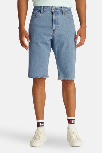 Shorts de jeans en denim bleu clair de TOMMY JEANS, avec des baskets blanches et des chaussettes à logo.