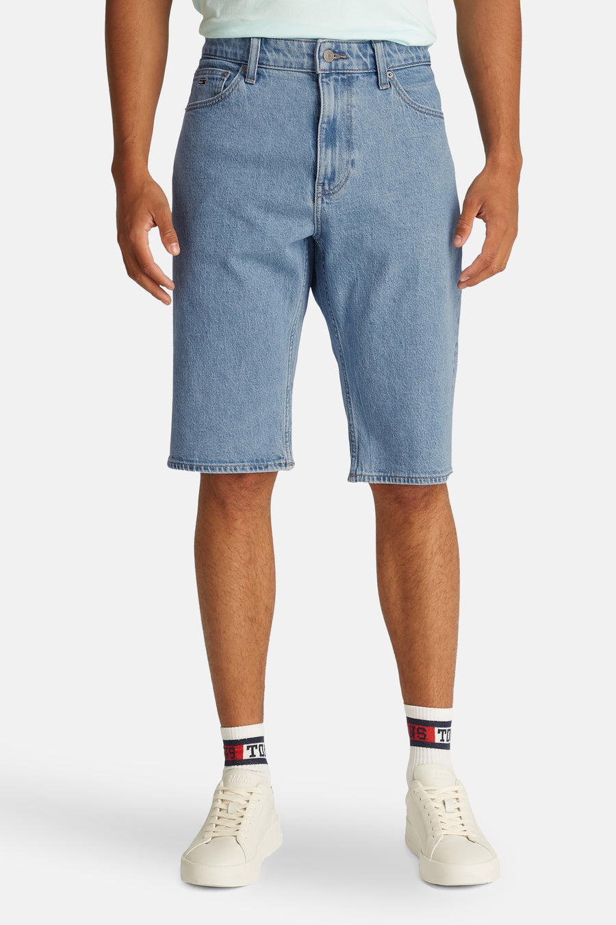 Shorts de jeans en denim bleu clair de TOMMY JEANS, avec des baskets blanches et des chaussettes à logo.