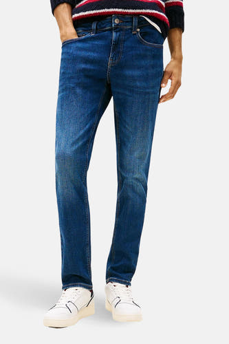 SCANTON donkerblauwe denim jeans slim van TOMMY JEANS, gedragen met een gestreepte trui en witte sneakers.