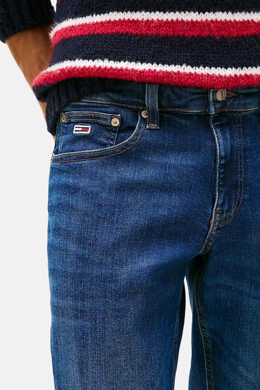 Donkerblauwe slim jeans van TOMMY JEANS, met merklogo op de zak en gestreept shirt.
