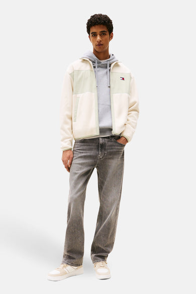 Manteau beige de TOMMY JEANS avec un hoodie gris et des jeans gris.