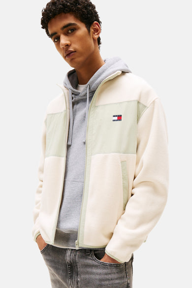 Manteau en polaire beige de TOMMY JEANS, avec des accents verts clairs et une hoodie grise en dessous.