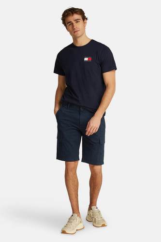 Shorts bleus de TOMMY JEANS, avec des poches cargo et associés à un T-shirt bleu marine et des baskets beige.