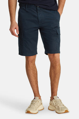 Shorts bleus de TOMMY JEANS, avec poches, portés avec des baskets blanches.