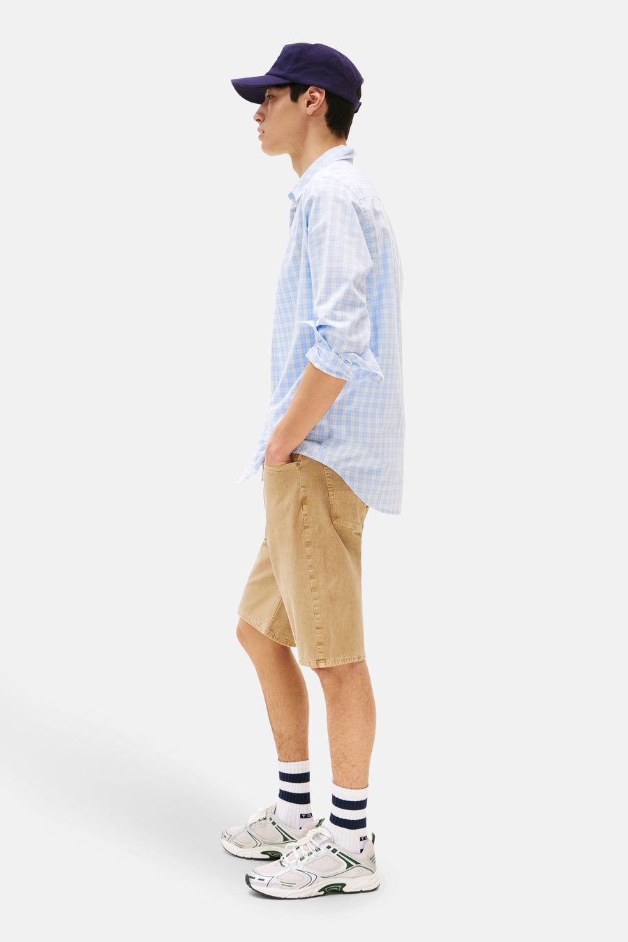 Jean court beige de TOMMY JEANS, avec une texture distinctive, associé à un chemisier rayé bleu et une casquette bleu marine.