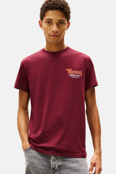 T-shirt rouge à manches courtes de TOMMY JEANS, porté par un modèle avec des jeans gris.