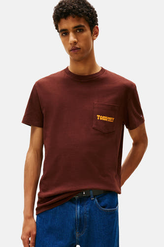 T-shirt brun à manches courtes de TOMMY JEANS, avec une poche poitrale logo logo et associé à un jean.