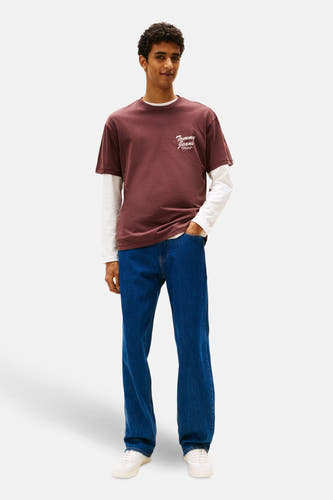 T-shirt brun à manches courtes de TOMMY JEANS, associé à un t-shirt blanc à manches longues et un jeans bleu.