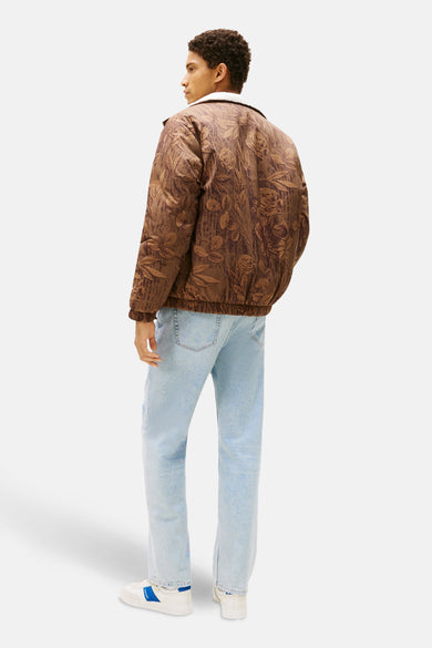 Manteau court brun de TOMMY JEANS avec motif floral, associé à des jeans bleu clair et des baskets blanches.