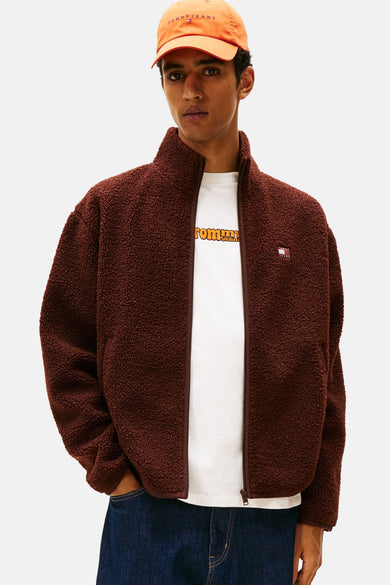 Veste brune de TOMMY JEANS avec une texture sherpa, portée sur un T-shirt blanc et des jeans bleus.