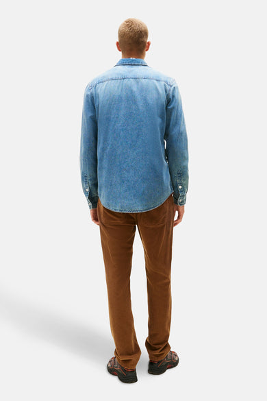 T-shirt en jeans de denim bleu mid de TOMMY JEANS, dos du modèle, associé à un pantalon corduroy marron et des baskets.