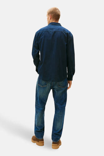 Chemise en denim bleu marine de TOMMY JEANS, vue de dos, associée à des jeans et des chaussures marrons.