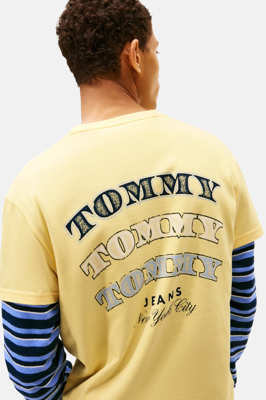 Achterkant van een geel Tommy Jeans sweatshirt met gestreepte mouwen.
