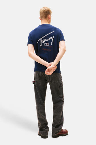 Blauw T-shirt met korte mouwen van TOMMY JEANS, met grafische print op de rug, gecombineerd met een donkere jeans.
