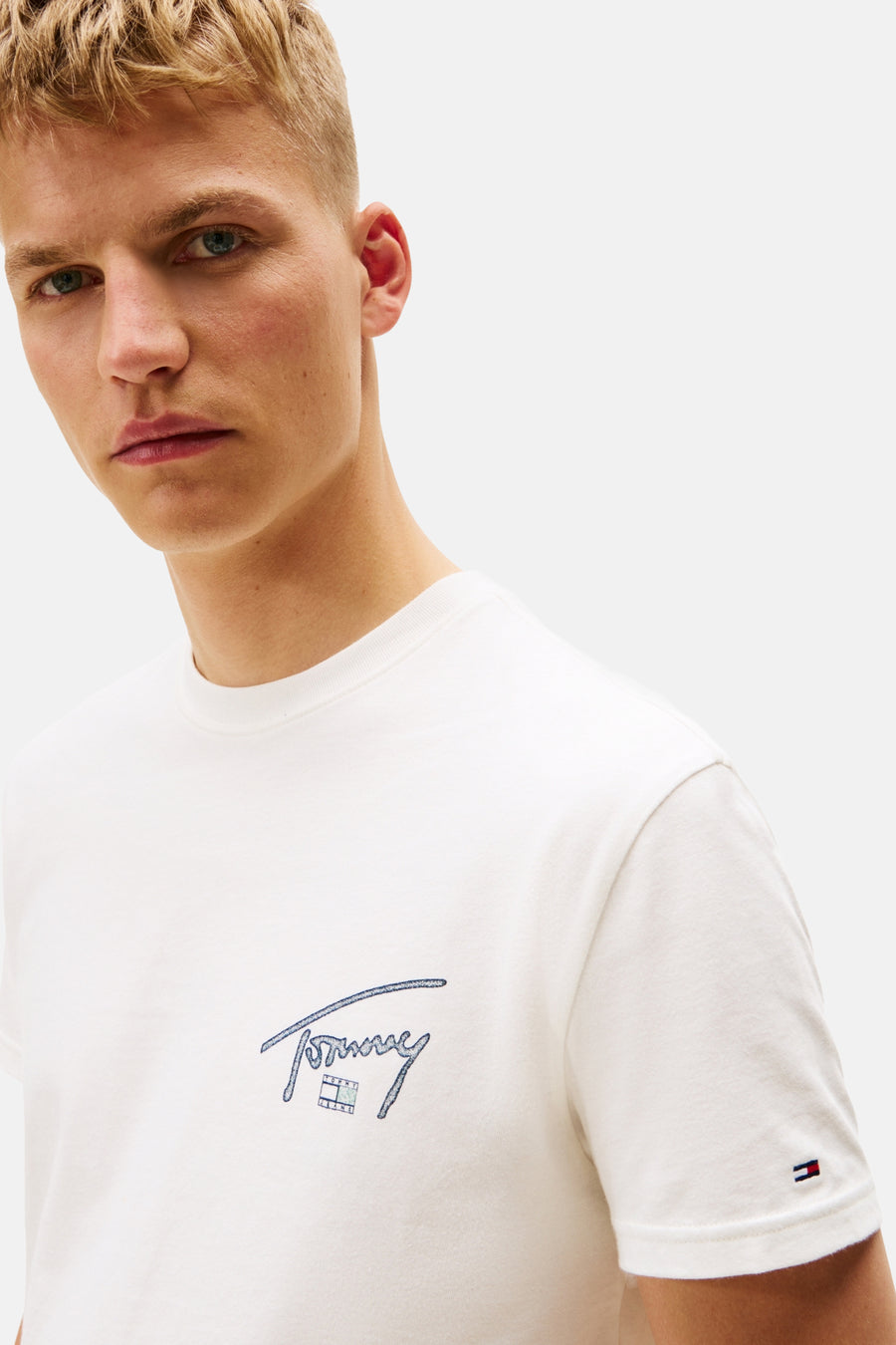 Een witte T-shirt met "Tommy" logo, gedragen door een man.