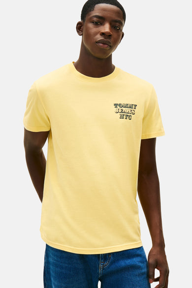 T-shirt jaune à manches courtes de Tommy Jeans, stylé avec un pull rayé sur les épaules et des jeans bleus.