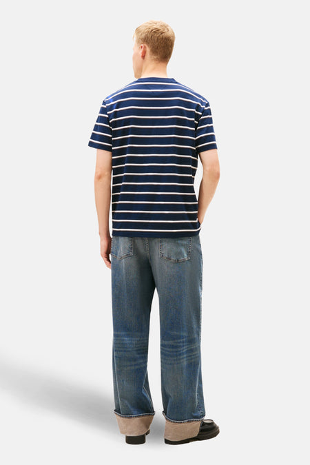 Man van achteren gezien, gestreept shirt, jeans met omslag, zwarte schoenen.
