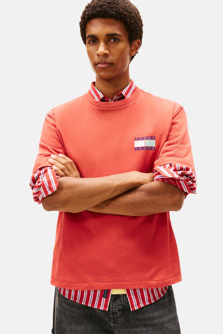 T-shirt rouge à manches courtes de Tommy Jeans, avec un chemisier rayé en dessous et des jeans larges gris foncé.