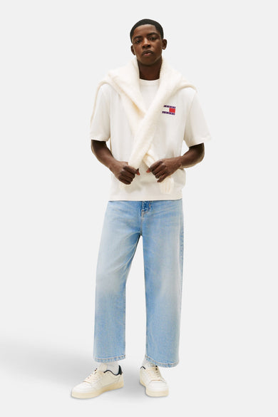 Wit T-shirt met korte mouwen van Tommy Jeans, met sjaal over de schouders en lichtblauwe jeans.
