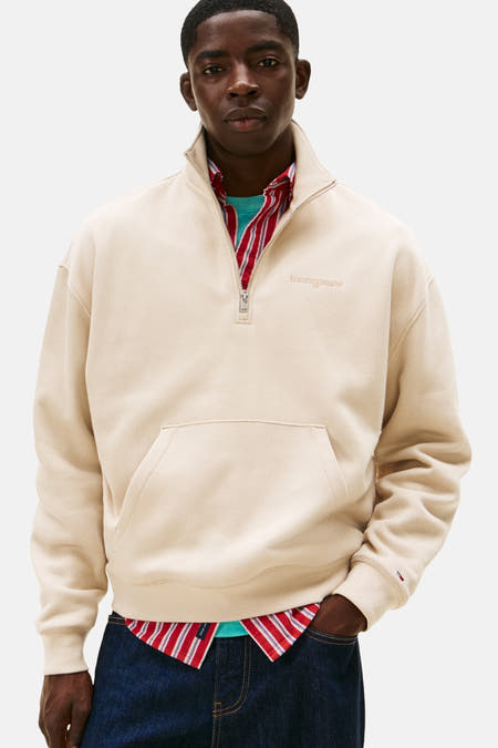 Gilet beige de TOMMY JEANS, avec un chemisier rayé dessous et des pantalons larges foncés.