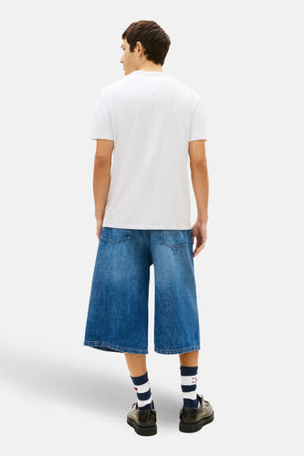 T-shirt gris à manches courtes de TOMMY JEANS, vue de dos, associé à un short en jean ample et des chaussettes rayées.