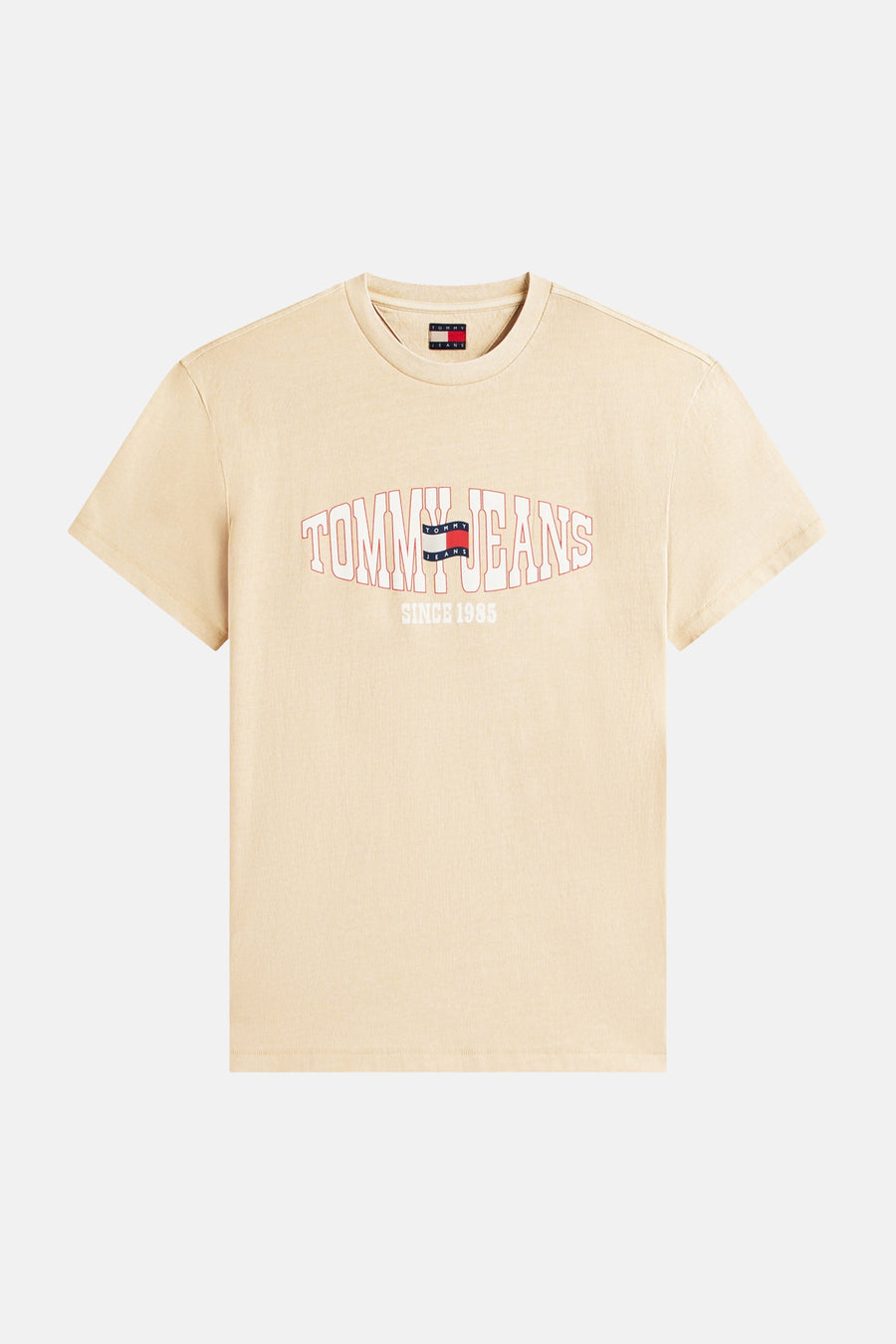 T-shirt beige de TOMMY JEANS avec un logo rouge et blanc incurvé 'TOMMY JEANS SINCE 1985' sur le devant.