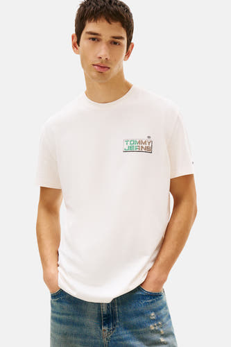 T-shirt écru à manches courtes TOMMY JEANS, avec un imprimé logo, porté avec un short en jean et des chaussures marron.