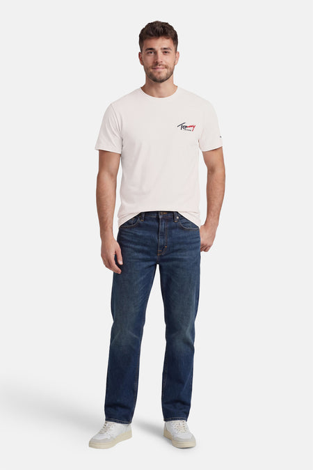 Witte korte mouwen T-shirt van TOMMY JEANS met klein logo op borst, gedragen met donkerblauwe jeans en witte sneakers, front view