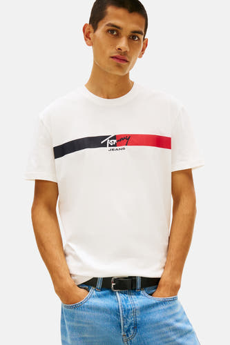 T-shirt blanc à manches courtes de TOMMY JEANS, avec un pull bleu marine sur les épaules et un jean bleu clair.