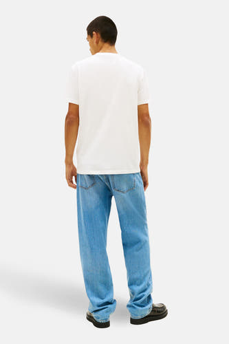 T-shirt blanc à manches courtes de TOMMY JEANS, vu de dos, associé à un jean décontracté et des chaussures noires.