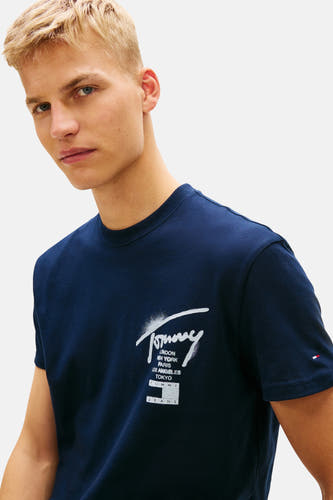 T-shirt bleu à manches courtes de Tommy Jeans, avec un logo et divers noms de villes sur le devant.