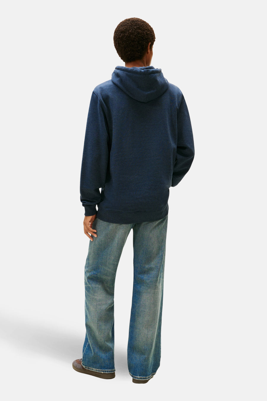 Achterkant van een persoon in blauwe hoodie en jeans.