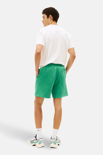 Short vert de TOMMY JEANS, vu de dos, avec chaussettes blanches et baskets.