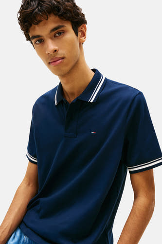 Polo bleu à manches courtes de TOMMY JEANS, avec des rayures blanches le long du col et des manches.