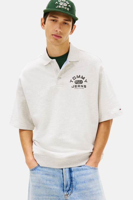 Polo grise à manches courtes de TOMMY JEANS, avec un imprimé logo sur la poitrine, combinée avec un short en jean et des chaussures marron.