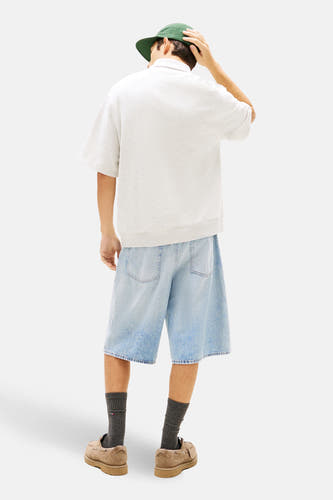 Polo grise à manches courtes de TOMMY JEANS, avec short en jean, chaussettes et chaussures, vue de dos.