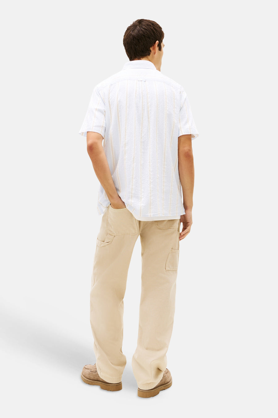 Chemise bleue à manches courtes TOMMY JEANS, à rayures verticales, portée avec un pantalon cargo kaki et des chaussures marron, dos.