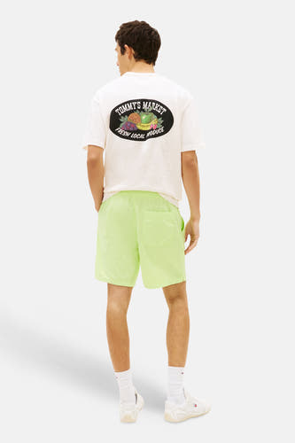 Short vert lime de TOMMY JEANS en tissu légèrement brillant et froissé, porté par un homme vu de dos.