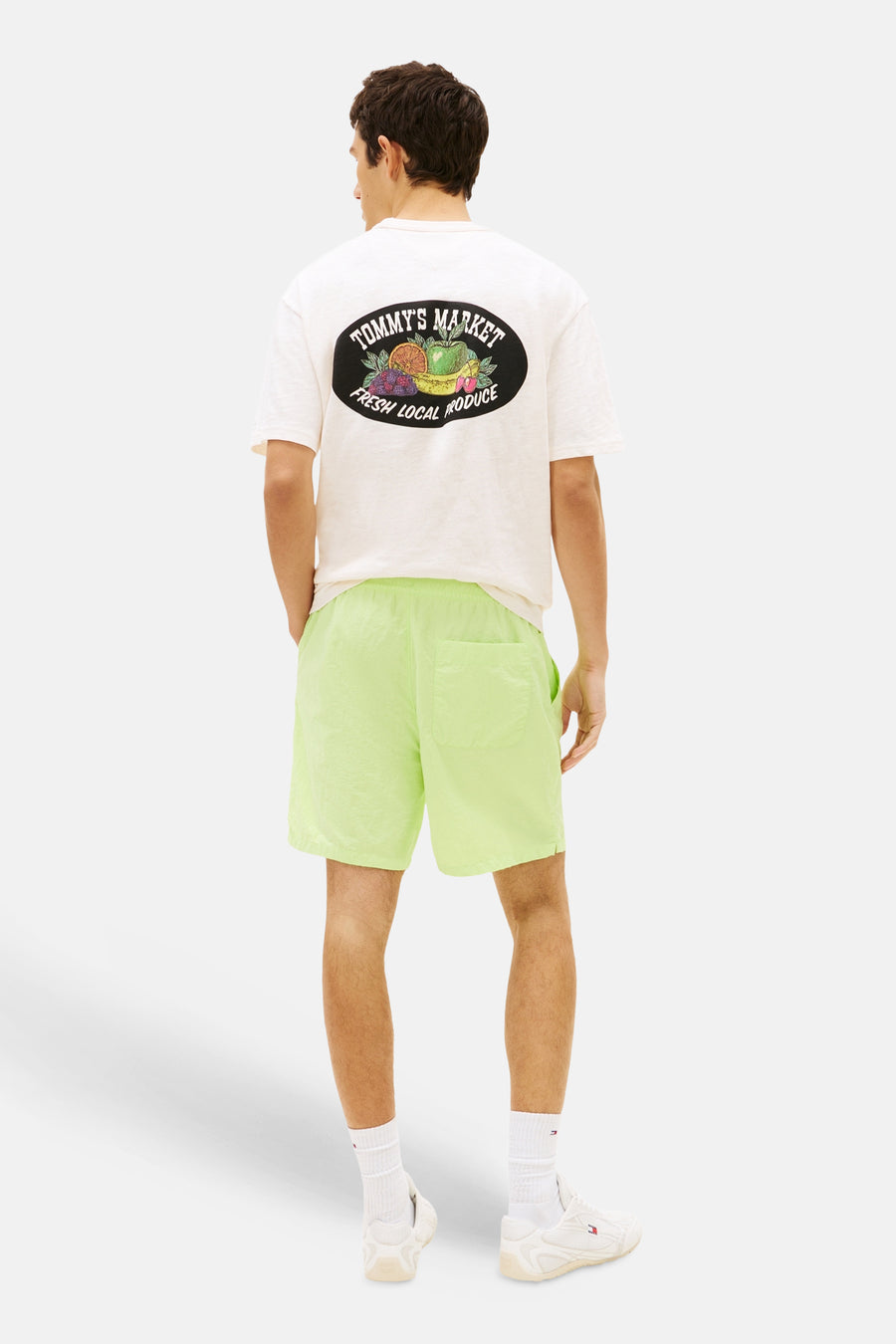 Short vert lime de TOMMY JEANS en tissu légèrement brillant et froissé, porté par un homme vu de dos.