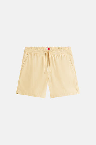 Short beige TOMMY JEANS avec une taille élastique, un cordon de serrage, des poches latérales et de petites fentes sur le bas.