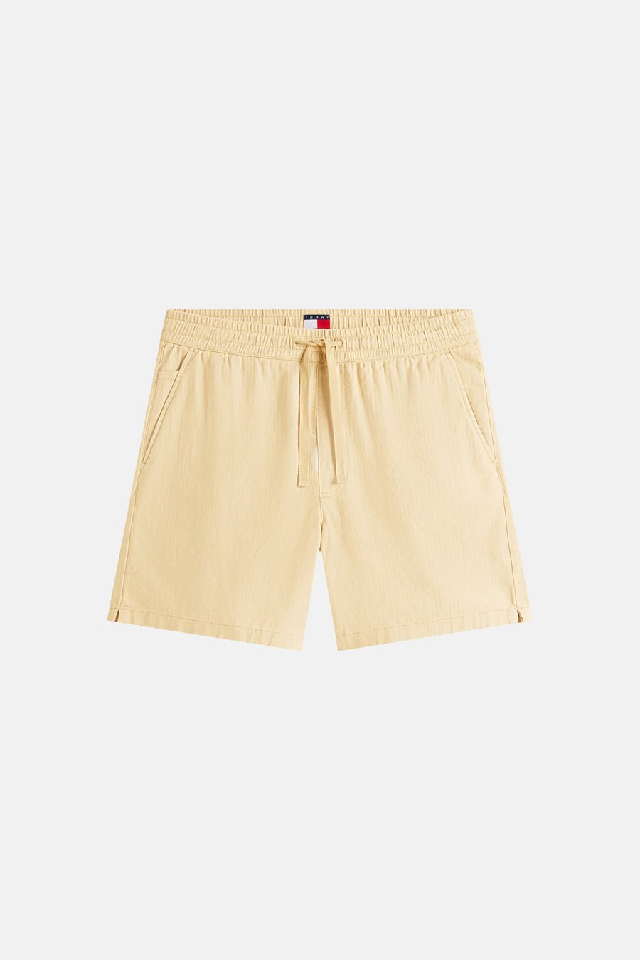 Short beige TOMMY JEANS avec une taille élastique, un cordon de serrage, des poches latérales et de petites fentes sur le bas.