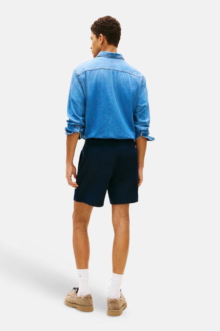 Short bleu de TOMMY JEANS, vu de dos, avec une chemise en jean et des chaussures marron.