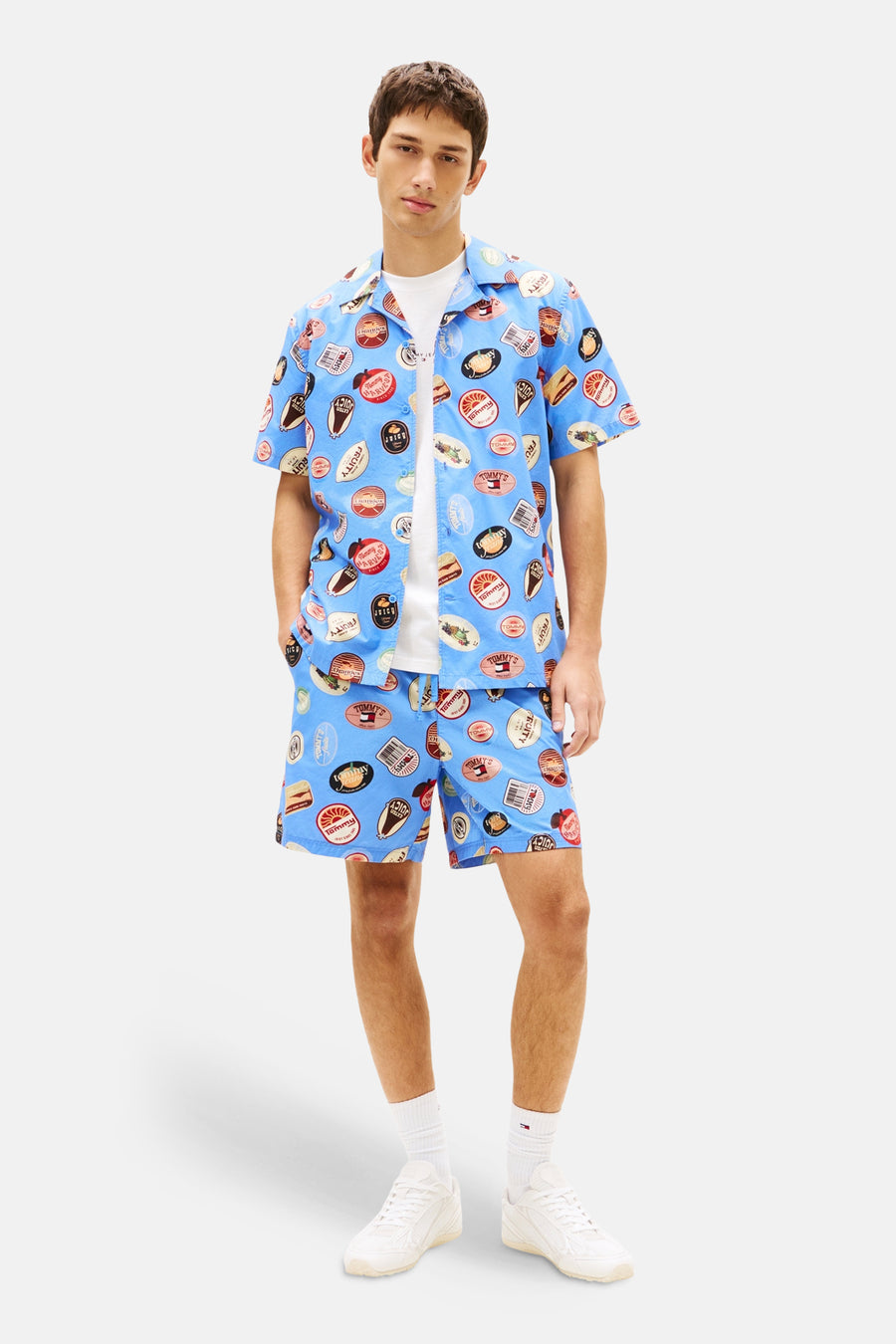 Blauwe short met print van Tommy Jeans, gedragen met een wit T-shirt en witte sneakers.
