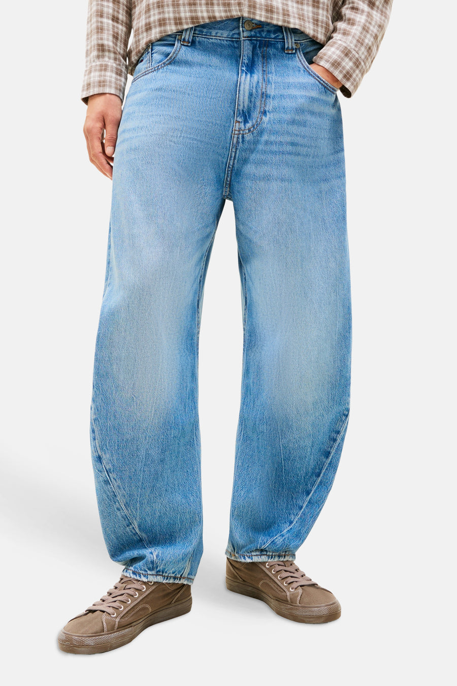 Jean bleu clair à coupe spéciale de TOMMY JEANS, combiné avec une veste bleu foncé, une chemise à carreaux et des baskets marron.