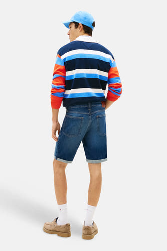 Short en jean en denim bleu marine de TOMMY JEANS, vu de dos, avec ourlets retroussés et poches arrière, stylisé avec un polo rayé.